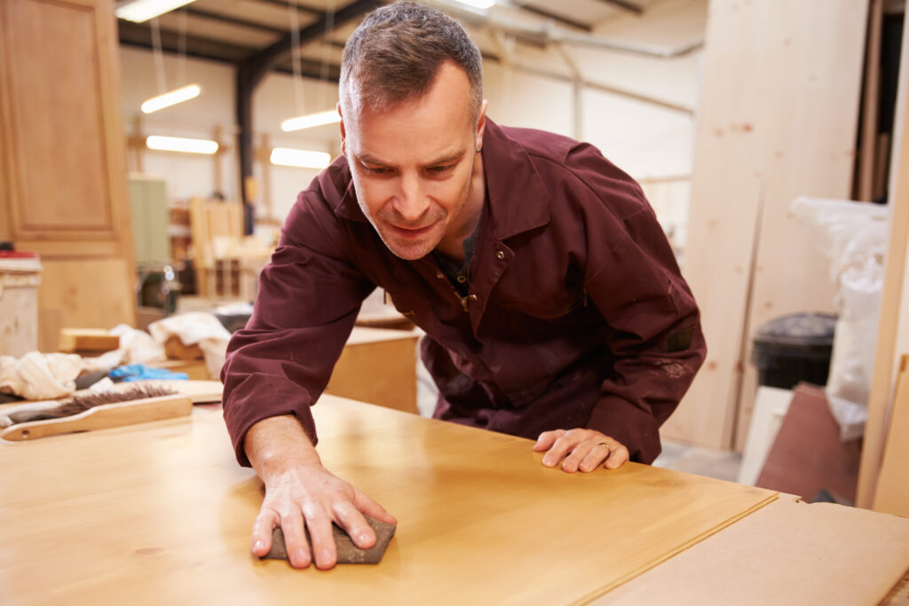 Craftsman hand-sanding a large solid wood tabletop