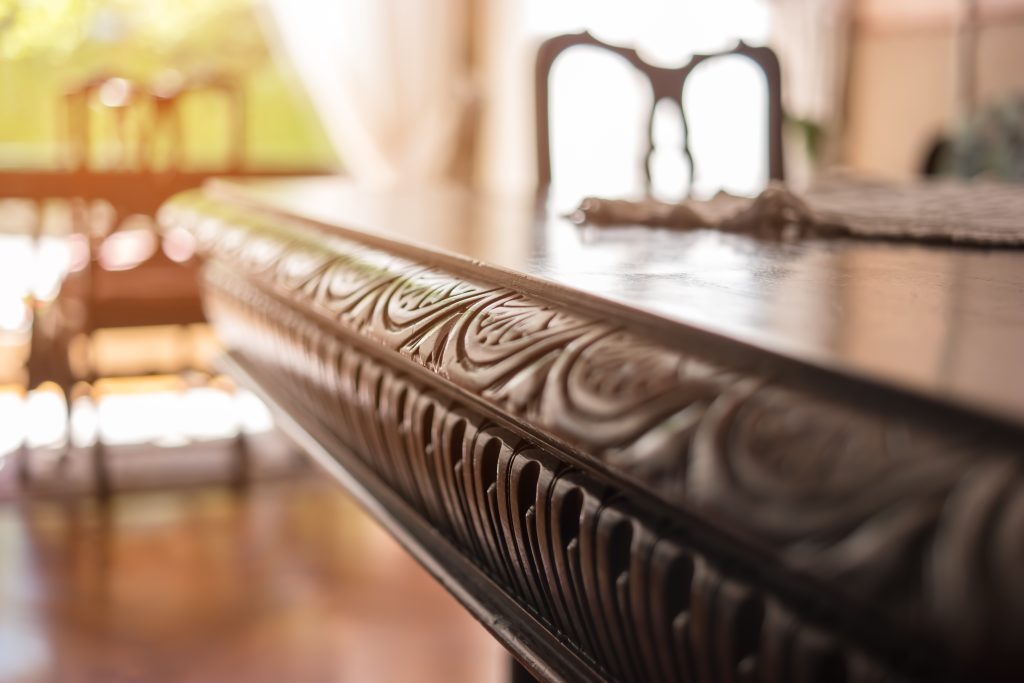 Close-up of a carved edge on a classic wood dining table in sunlight
