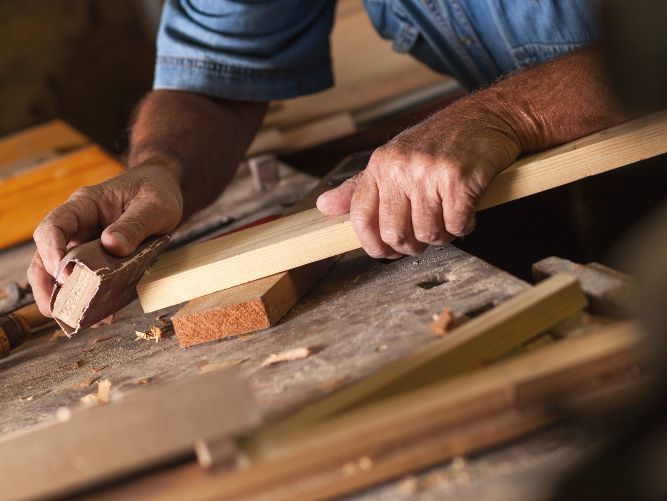 Experienced carpenter cutting a board by hand in his workshop