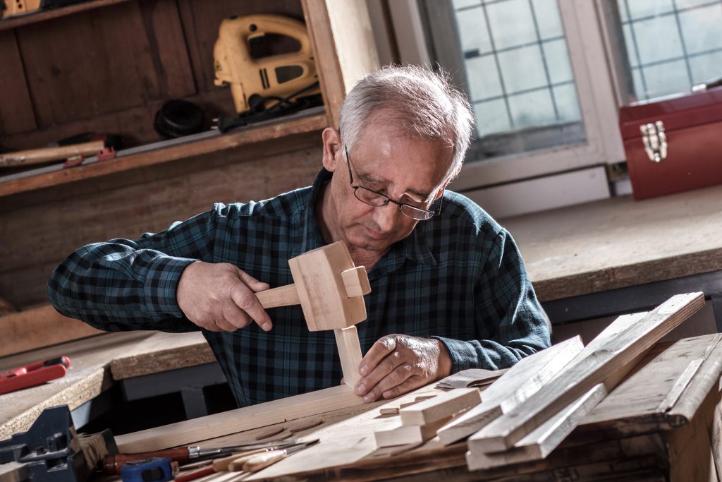 Senior woodworker tapping a joint with a wooden mallet