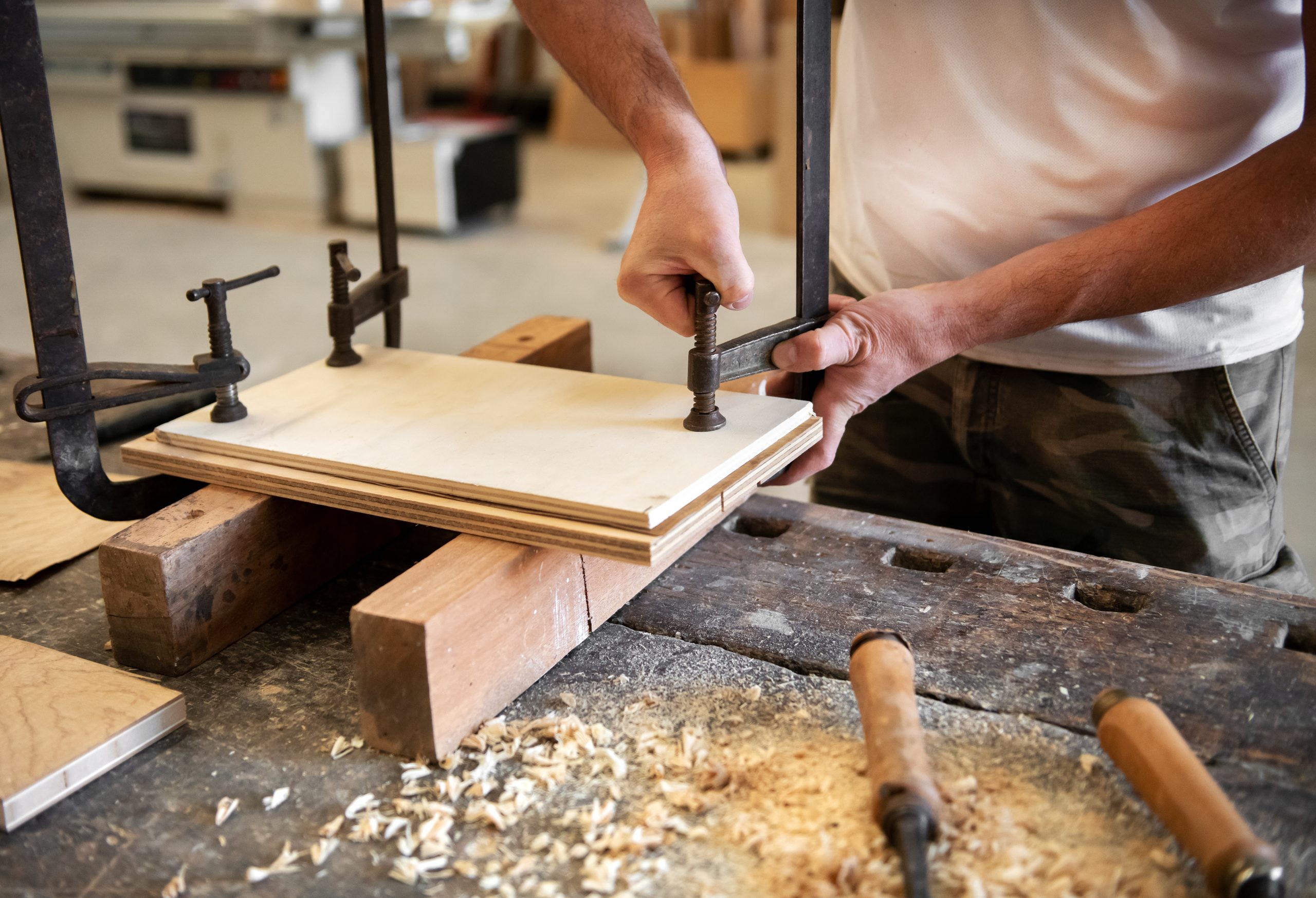 Wood panel clamped in a vise on a workbench with chisels