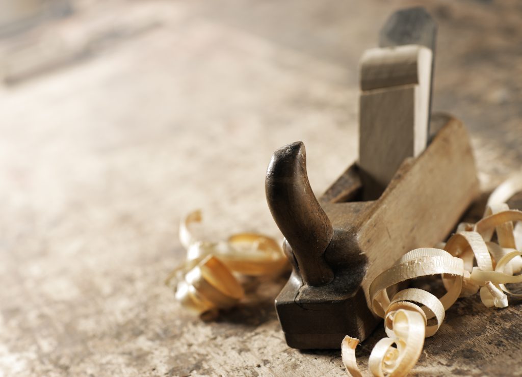 Wooden hand plane resting among curled wood shavings