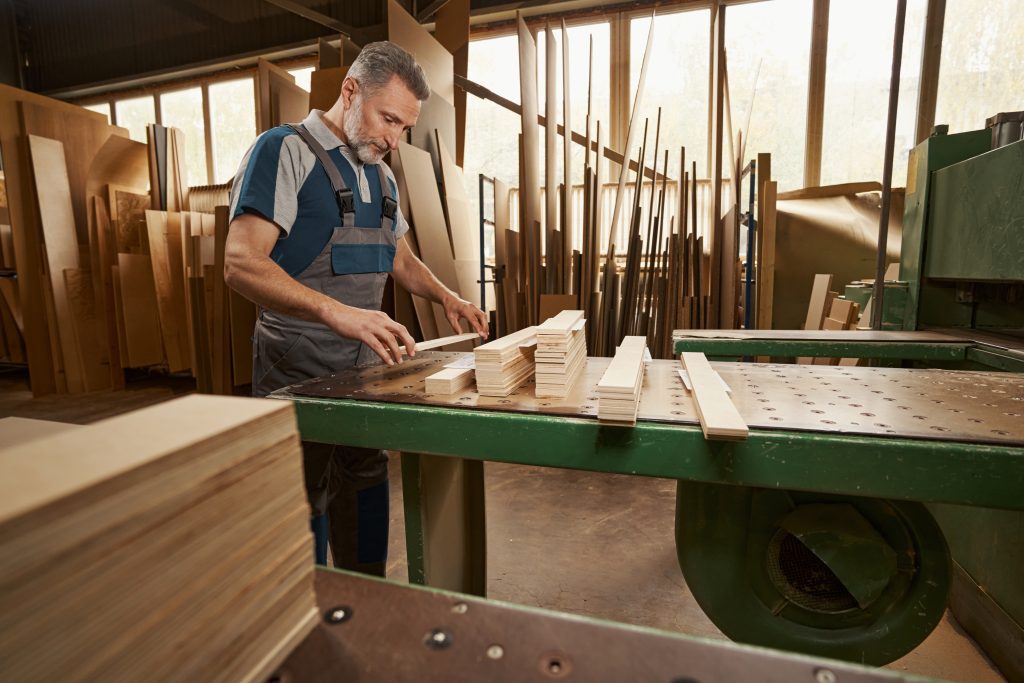 Woodworker cutting lumber at a workbench in a furniture shop